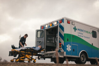 A Mercy Health paramedic assists a patient outside of the ambulance